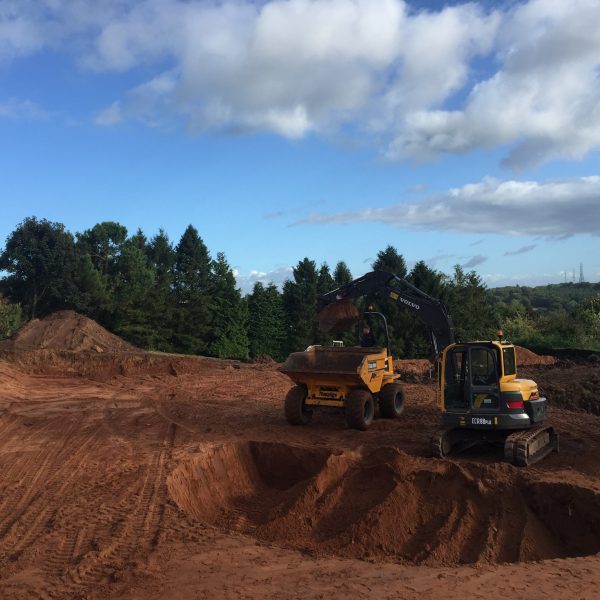2 yellow diggers digging holes on a worksite